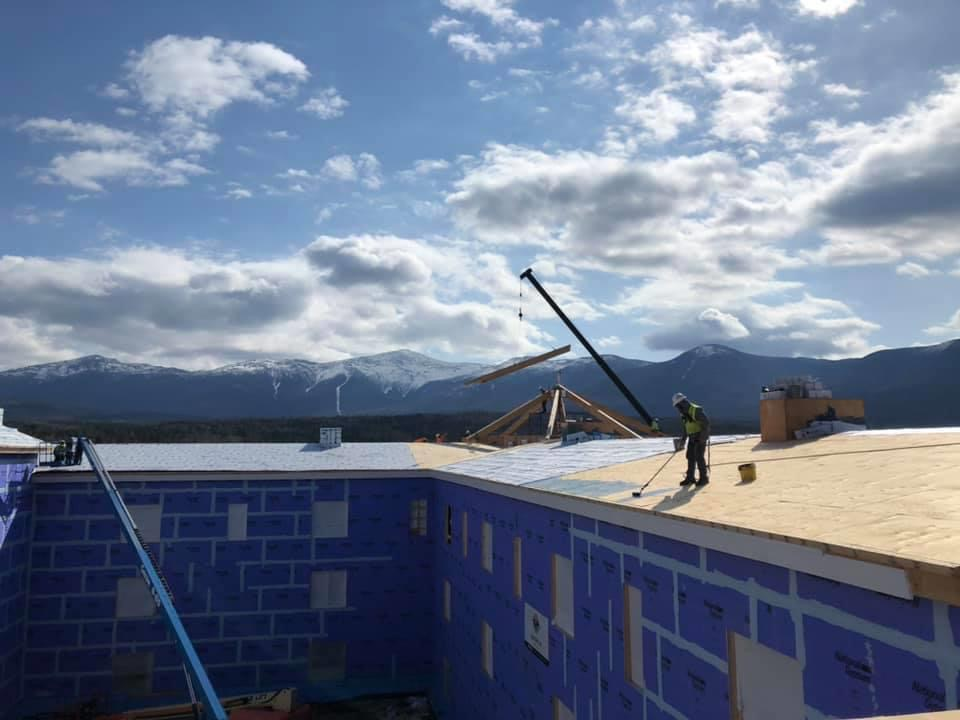 Carpenters framing roof structure at Omni Mount Washington Resort with mountains in background