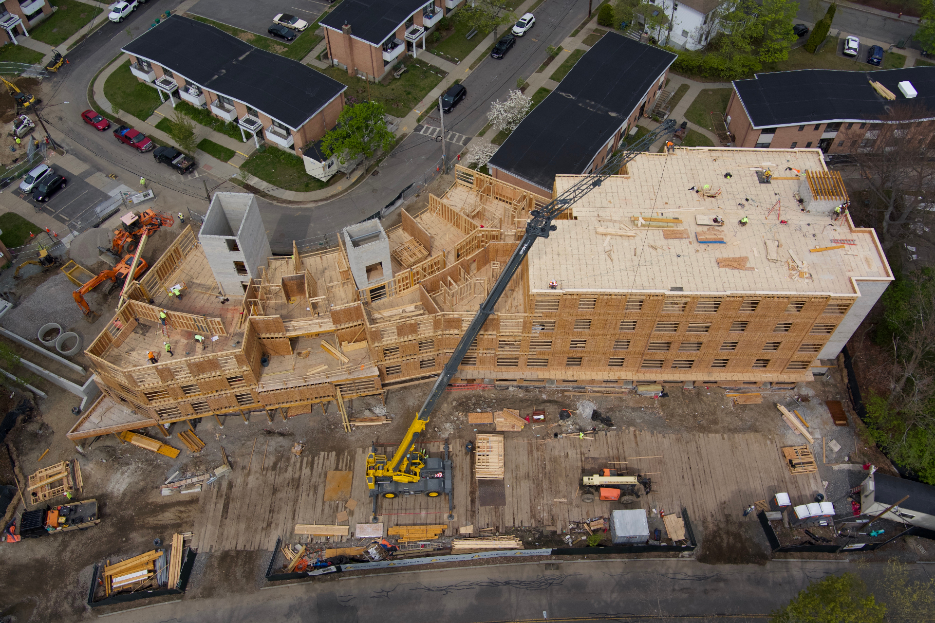 Aerial drone view of a large multi-story wood-framed building under construction with crane